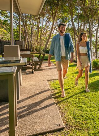 Couple walk through back garden by the beach at Mildenhall cottage in Byron Bay, North Coast